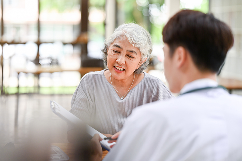 A happy Asian old lady is talking about health treatments and being checked on by a doctor.